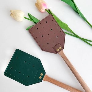 Vintage fly swatter with leather head and long beech wood handle on a white surface