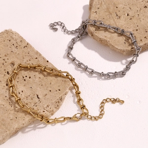 Detailed view of industrial chain anklets in gold and silver finish on stone props