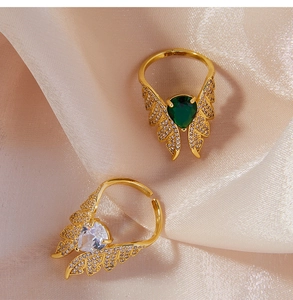 Macro shot of gold wing rings featuring green and white pear-cut zircon on silk