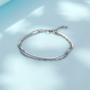 Double-layered snake and bead chain bracelet in polished steel on a sky blue background