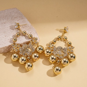 Elegant gold vintage tassel earrings with zircon flower studs on a textured stone display