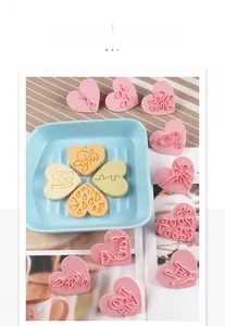 Detail of pink heart-shaped cookie molds with I Love You and Kiss embossed patterns
