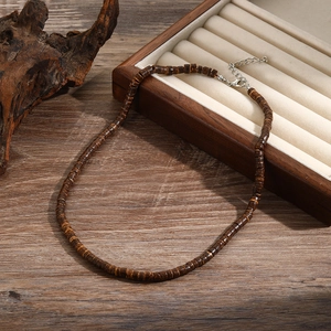 Details einer Boho-Holzperlenkette mit Metallverschluss auf rustikalem Holzhintergrund