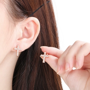 Detail of rose gold cross earrings with micro-pave white crystals on the earlobe