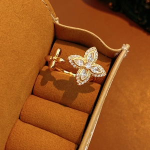 Détail de bague trèfle dorée avec zircons sur boîte à bijoux en velours marron