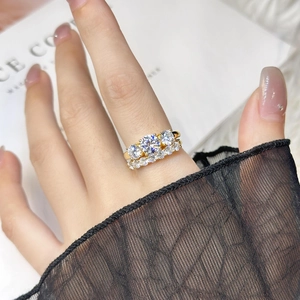 Detailed view of a gold ring featuring three large diamonds on a model's hand