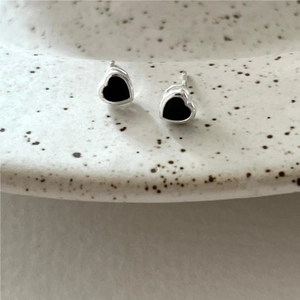 Close-up of black heart-shaped S925 silver stud earrings on a ceramic dish