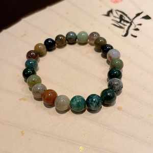 Detailed view of Shoushan stone beads on gold-flecked paper with Chinese calligraphy