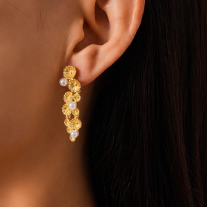 Close-up of vintage gold flower drop earrings with white pearls on a female model