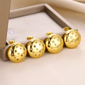 Golden round stud earrings with multi-color zircon stars on a jewelry box edge