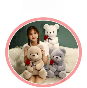 Detail of plush teddy bears in white beige and grey holding red roses with soft textures