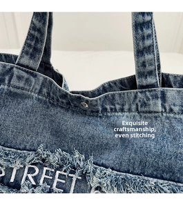 Détail du sac cabas en denim avec broderie STREET blanche et coutures renforcées