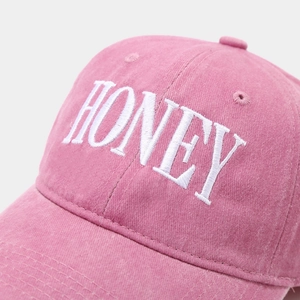 Pink washed cotton baseball cap featuring white HONEY letter embroidery on the front