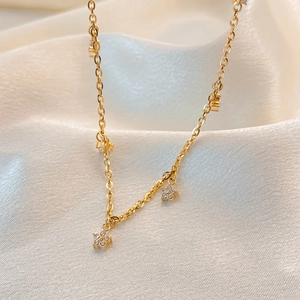 Close-up of a gold-plated flower necklace with zircon crystals on white silk fabric