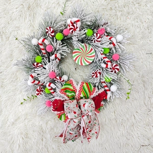 Detail of Christmas wreath with candy canes and snow-covered pine needles on plush white rug