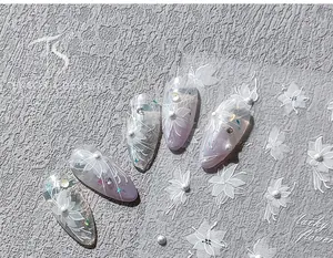Macro shot of 3D white flower nail art stickers with pearls on purple manicure tips