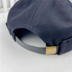 Detail of navy cotton docker hat featuring a leather strap and vintage metal buckle