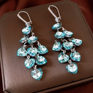 Detailed macro view of cascading heart-shaped blue crystals on silver tassel earrings