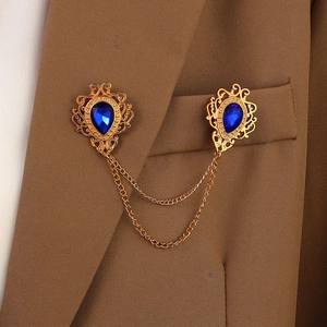 Detail of vintage gold collar pin set with blue water-drop gems on a brown suit jacket