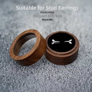 Detail of round walnut wood ring box with clear lid showing leaf-shaped earrings