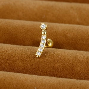 Macro d'un piercing d'oreille en acier doré avec zircons sur fond de velours brun