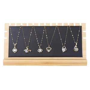 Golden necklaces with white zircon pendants on a premium bamboo and leather display stand