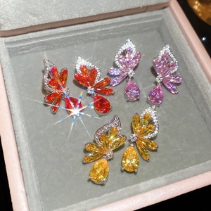 Detail of three pairs of zircon butterfly wing earrings in orange pink and yellow hues