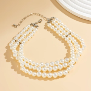 Detail showing a triple-layer pearl necklace with silver lobster clasp and extension chain