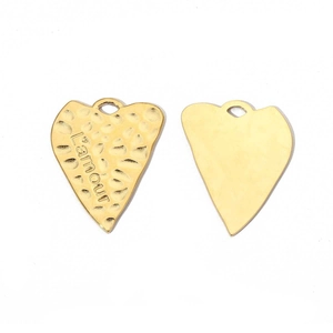 Detailed macro view of golden heart charms with hammered texture and L'amour engraving