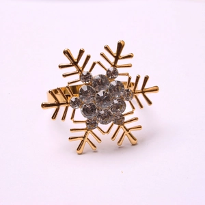 Close-up of golden snowflake napkin ring featuring sparkling rhinestones on white backdrop