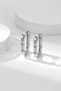 Close-up of silver square hoop earrings with micro-set zircon stones on white display
