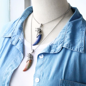 Detail van wolfskop hangers met blauwe lapis en natuursteen aan een zilveren kralenketting