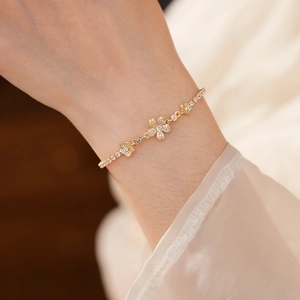 Primo piano di un elegante bracciale floreale dorato con zirconi lucidi su un polso