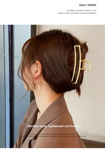 Detail of matte gold metal claw clip and twisted hoop earrings on styled hair