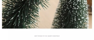 Close-up of mini flocked Christmas trees with snow effect on wooden background