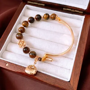18K gold plated tiger eye beaded bracelet with lucky pendant on a wooden display