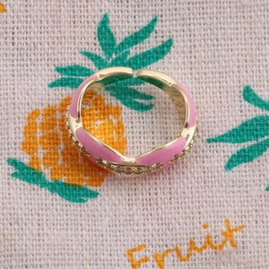 Detail of gold-plated open ring featuring pink enamel finish and shimmering zircon accents