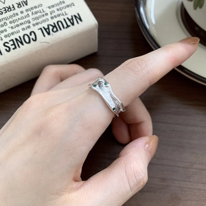 Detailed view of an irregular S925 silver ring with green gemstones on a model's finger