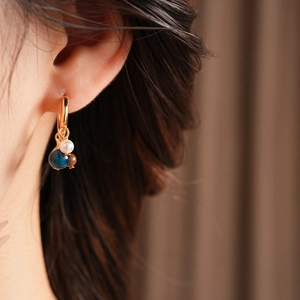 Close-up of vintage hoop earring with pearl and tiger eye bead on a model ear