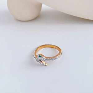 Bague serpent dorée minimaliste avec cristaux et yeux en gemmes vertes sur fond ivoire