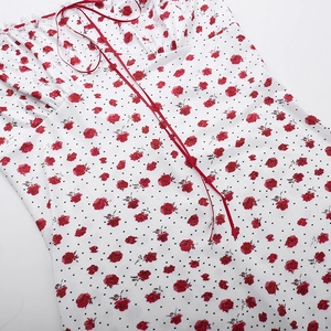 Detalle de vestido con estampado de rosas rojas, lunares, encaje blanco y lazo rojo