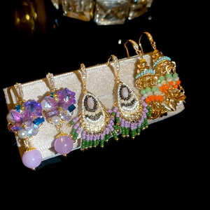 Detailed view of handmade beaded fringe earrings with purple, green and gold crystals