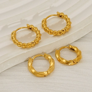 Detailed view of gold-plated stainless steel twisted hoop earrings on textured background