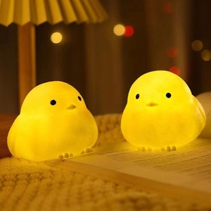 Close-up of two warm glowing chicken night lights on an open book in a cozy setting