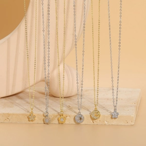 Detail of diverse flower and star pendants on gold and silver chains over stone