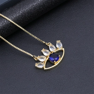 Detail of gold evil eye necklace with blue round stone and teardrop crystals