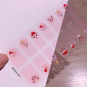 Gros plan de stickers à ongles de Noël roses avec motifs de Père Noël et de rennes