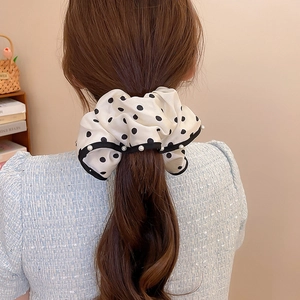 Macro detail of oversized white polka dot scrunchie with delicate pearl edge trim