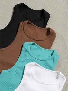 Detail of ribbed knit yoga tanks in four colors on a textured neutral background