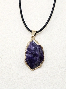 Détail macro du pendentif en pierre naturelle violette avec bord doré et cordon noir